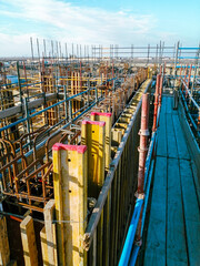 A construction site with scaffolding and a blue sky in the background. Scene is one of progress and hard work