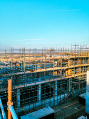 A construction site with scaffolding and a blue sky in the background. Scene is one of progress and hard work