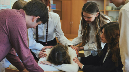 A high school girl cries and her friends comfort her.