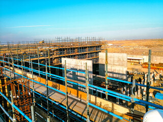A construction site with scaffolding and a blue sky in the background. Scene is one of progress and hard work