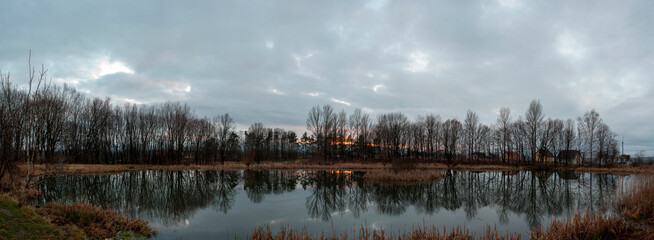 Panoramic photo during steel hour on an almost windless evening with a smooth lake.