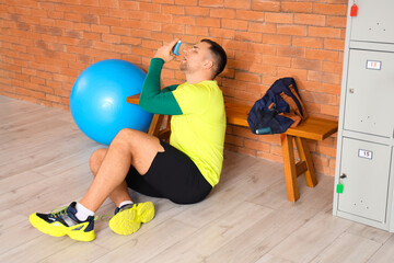 Sporty young man with asthma attack using inhaler in gym