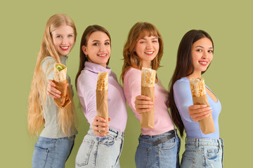 Young women with doner kebabs on green background