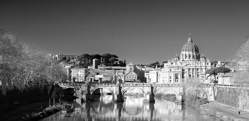 The River Tiber with historic building reflecting in the calm blue water, with St Peter's Basilica...