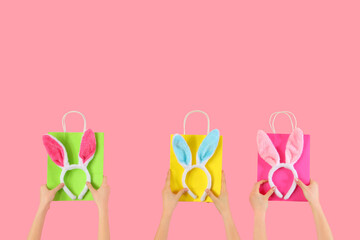 Women with shopping bags and bunny ears on pink background. Easter Sale