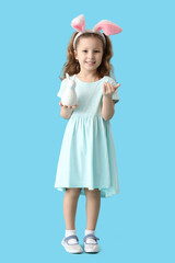 Cute little girl in bunny ears with rabbit on blue background. Easter celebration