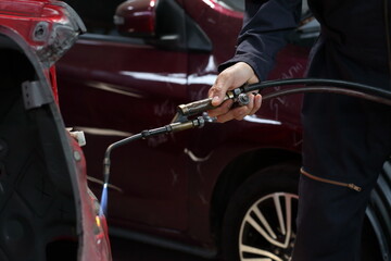 Obraz premium Auto mechanic working in garage. Repair service. Worker mechanics in uniform are working in auto service with lifted vehicle. Car repair maintenance.