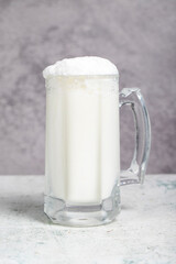 Sparkling buttermilk. Close-up. A glass of ayran on a gray background