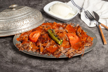 iskender kebab. Traditional Turkish cuisine flavor with tomato sauce and butter. iskender kebab on dark background