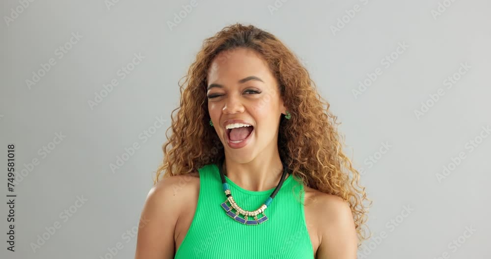 Wall mural Woman, fashion and wink with smile in studio on white background, happiness and necklace with trendy outfit. Closeup, female person and excited with colorful top for style, clothes and jewelry