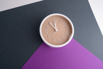 White alarm clock on a colored background. Fashionable minimalist style. Time, business and technology concept. Flat composition. View from above