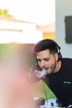 Portrait of a young dj smoking cannabis crazy during a party