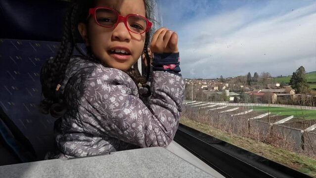 Little Latin girl enjoying train ride looking out window at scenery