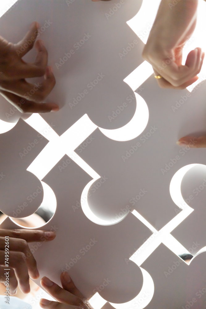 Poster below view of diverse corporate officer workers collaborate in office connecting puzzle pieces as pa