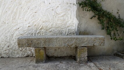 A light granite bench along the wall of an old abandoned house.