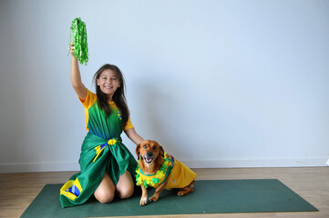menina sorridente com cachorro doméstico com roupas do brasil 