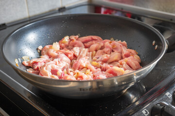 Frying chicken fillet slices with onion in frying pan