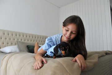 menina criança feliz a vontade em casa com cachorro de estimação filhote fofo de Dachshund 
