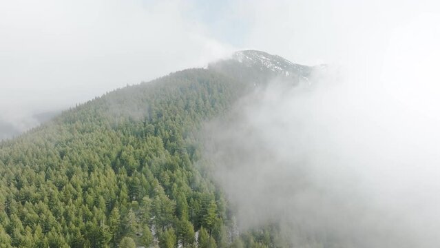 Drone orbits clockwise a ridge of the Mount Konarevo which is submerged in clouds in late winter
