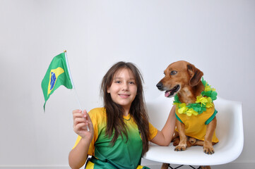 menina brasileira com cachorro , festa nas cores do brasil  - obrazy, fototapety, plakaty