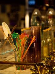 Vibrant cocktail stirrers in star shapes, glasses and golden tinsel on a bar counter, conveying a festive, celebratory mood