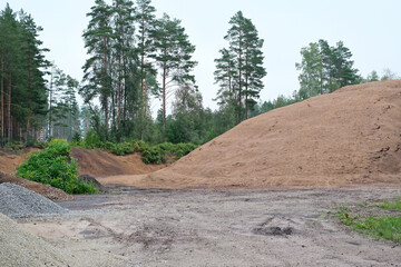 Two piles of dirt, gravel, and rocks, resting side-by-side on a dirt path in a sunny forest