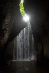 An incredibly beautiful waterfall in a cracked rock in the jungle on the popular island of Bali.