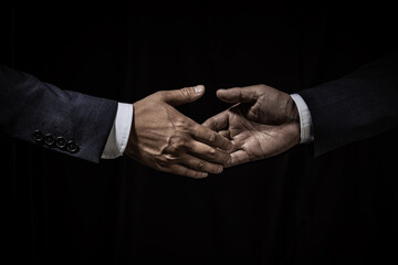 黒背景に握手をするビジネスマンの手のクローズアップ