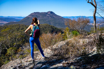 hiker girl looking at the peak of mount maroon from the top of mount may in mount barney national park, south east queensland, australia