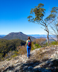 hiker girl looking at the peak of mount maroon from the top of mount may in mount barney national...