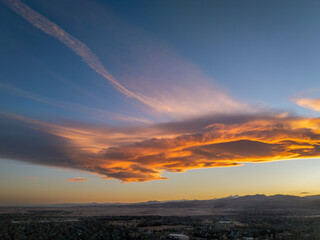 clouds and contrails over Rocky Mountains foothills and city of Fort Collins, Colorado, in sunrise light