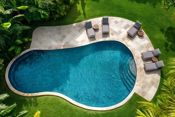  Aerial view of backyard of a modern villa with a rounded pool, with turquoise water, with sun loungers placed around the pool, surrounded by a green lawn with palm trees,concept of rest and relaxation © Наталья Лазарева