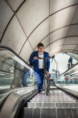 vertical portrait Businessman with Electric Folding Bike on Metro Escalator