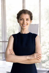 Vertical shot attractive satisfied and successful businesslady looking at camera, posing with arms-crossed in office. HR manager, company executive manager portrait, career, leadership and promotion