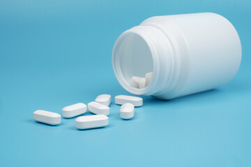 Long shaped white medical tablet isolated on blue background