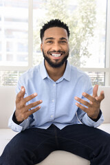 Happy handsome young African blogger man taking self video, speaking at camera, laughing, smiling,...