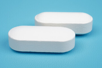 Long shaped white medical tablet isolated on blue background