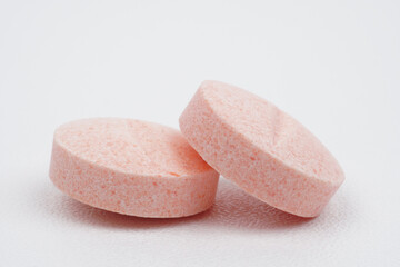 Single closeup pink medical tablet on white background