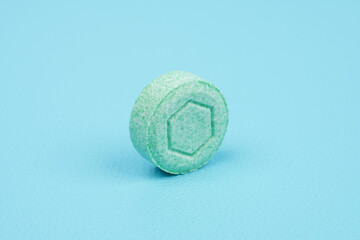 One green colored tablet against blue background
