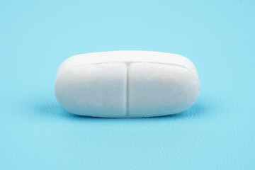 Long shaped white medical tablet isolated on blue background