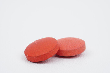 Closeup of two red tablets isolated on white background