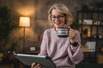 mature blonde woman with eyeglasses use digital tablet at home