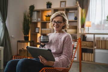 mature blonde woman with eyeglasses use digital tablet at home