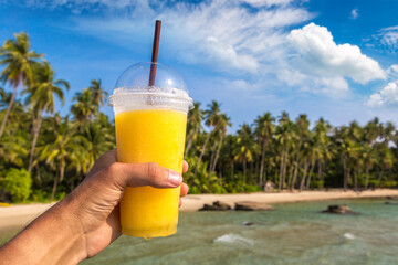 Hand holding a yellow smoothie glass