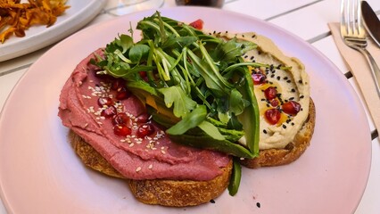 Tostada de humus de remolacha con rúcula, granada y semillas de amapola