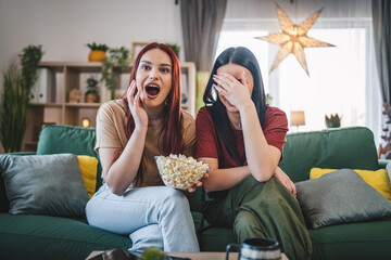 two women caucasian teenage friends or sisters watch movie tv at home