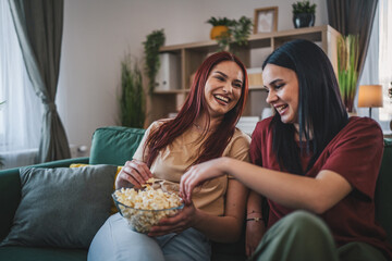 two women caucasian teenage friends or sisters watch movie tv at home