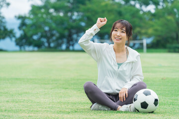 サッカーで勝利してガッツポーズするサッカーファン・サポーターの日本人女性
