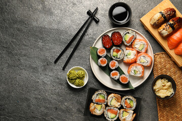Flat lay composition with delicious sushi rolls on dark grey table. Space for text