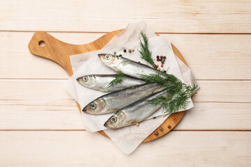 Fresh raw sprats, peppercorns and dill on light wooden table, top view